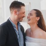 Evelin and Luke laughing together by the sea on Paros during their four-day wedding, filmed by Konstantinos Liopetas