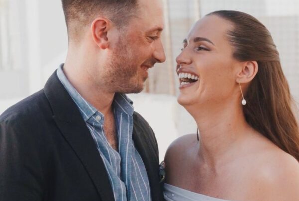 Evelin and Luke laughing together by the sea on Paros during their four-day wedding, filmed by Konstantinos Liopetas